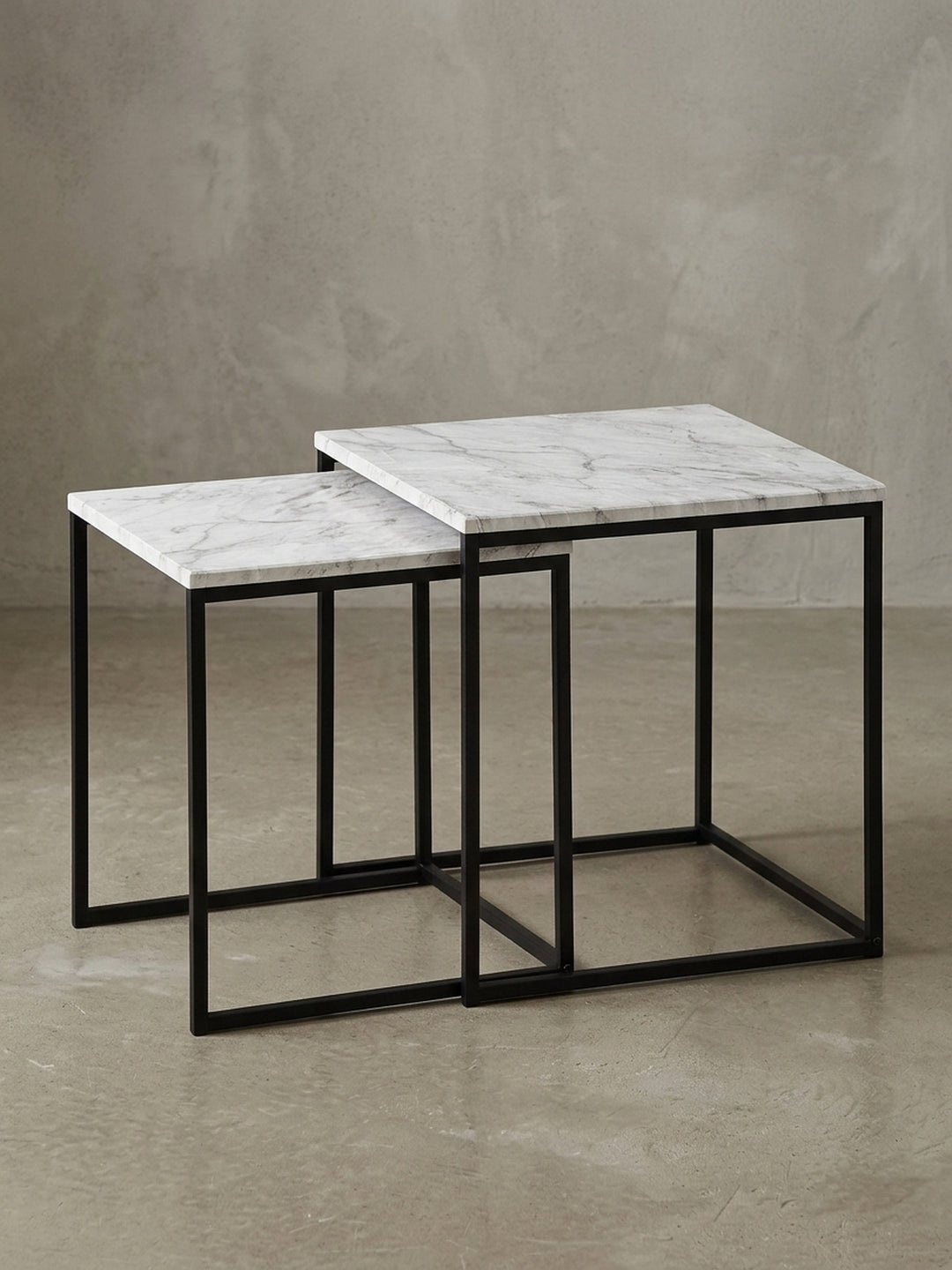 Design Beistelltisch in 3/4-Ansicht, zeigt die kubische Form und das Zusammenspiel der zwei ineinander verschachtelten Tische mit Marmor-Finish._
