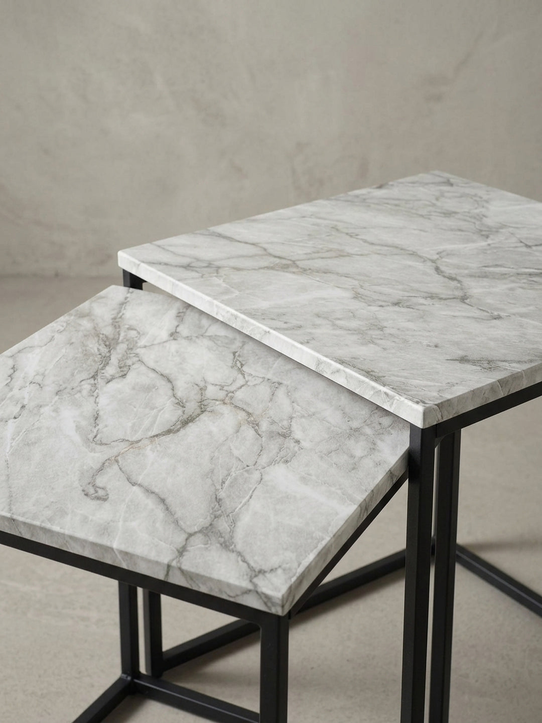 Nahaufnahme der Kante und des Gestells des Beistelltisches, die saubere Verarbeitung des Übergangs von der Marmor-Optik Platte zum schwarzen Metall wird gezeigt._