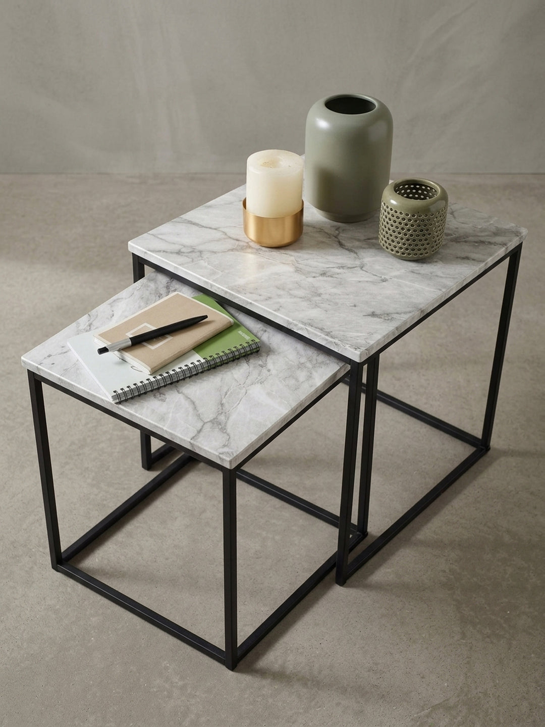 Nahaufnahme der Kante und des Gestells des Beistelltisches, die saubere Verarbeitung des Übergangs von der Marmor-Optik Platte zum schwarzen Metall wird gezeigt._