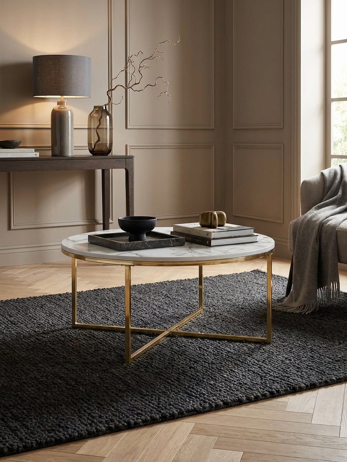 Eleganter runder Couchtisch mit weißer Marmor-Optik und goldenem Gestell, stilvoll inszeniert in einem modernen Wohnzimmer vor einem großen Sofa.