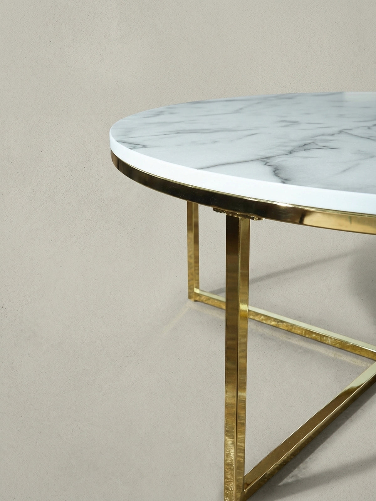 Makroaufnahme des Verbindungsstücks am goldenen Metallgestell, die die präzise Fertigung und das moderne Design des runden Wohnzimmertischs unterstreicht.