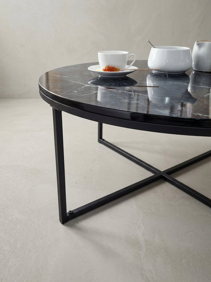 Nahaufnahme des Übergangs von der schwarzen Tischplattenkante zum filigranen Metallbein, die die saubere Verarbeitung des modernen Sofatisches unterstreicht._