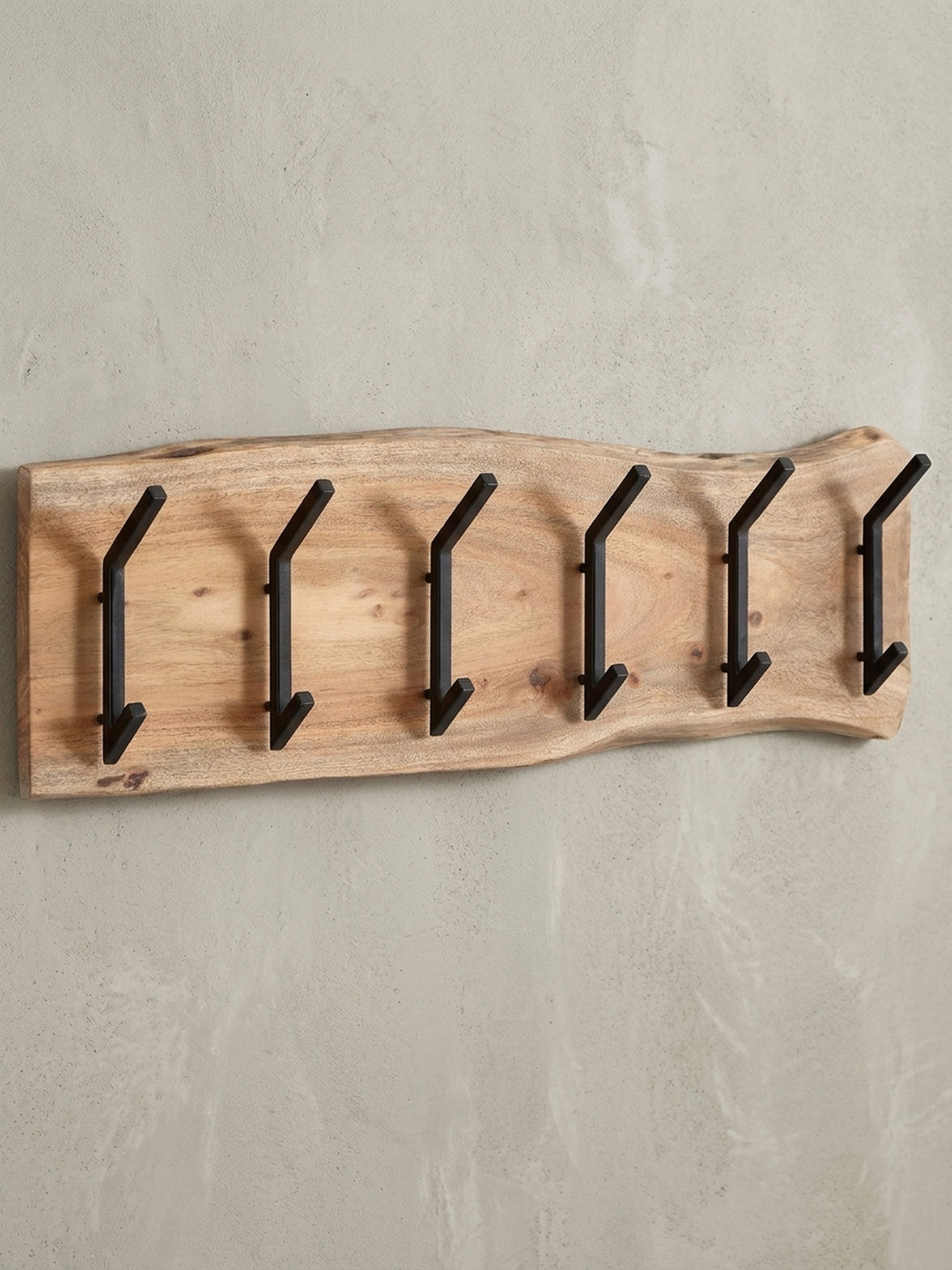 Moderne Wandgarderobe aus Akazienholz mit natürlicher Baumkante und sechs schwarzen Metallhaken, freigestellt vor weißem Hintergrund._