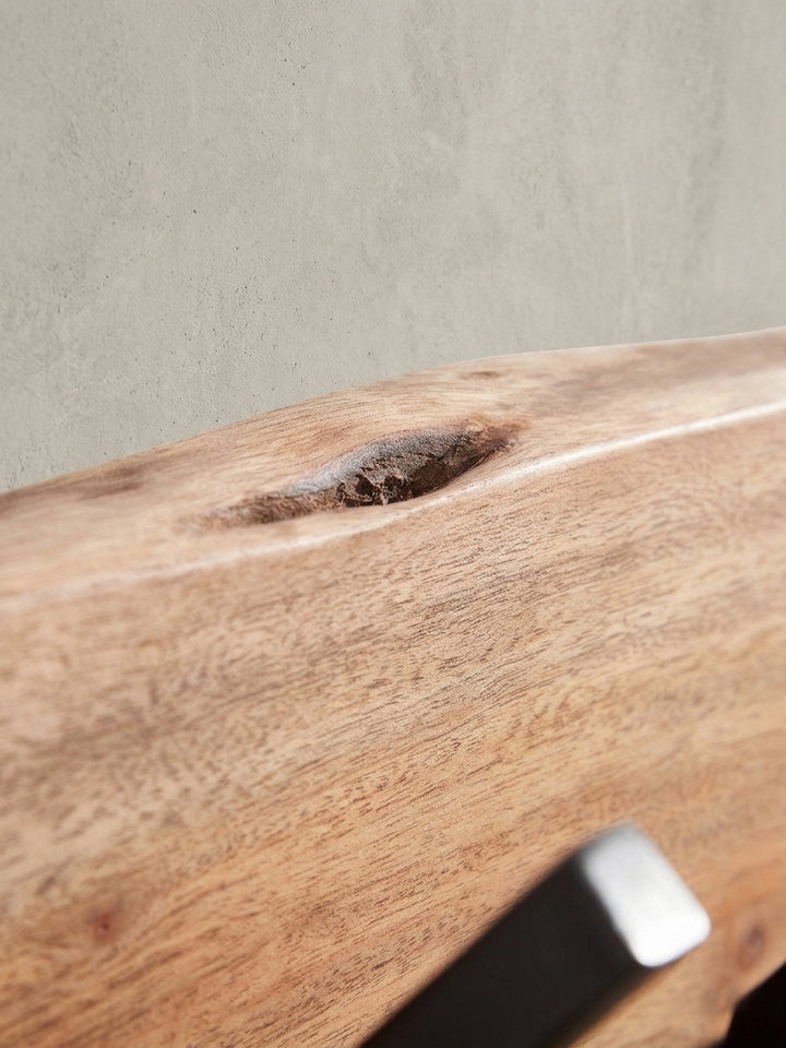 Detailaufnahme eines einzelnen, kantigen Garderobenhakens aus schwarzem Eisen auf der natürlich gemaserten Akazienholz-Rückwand._