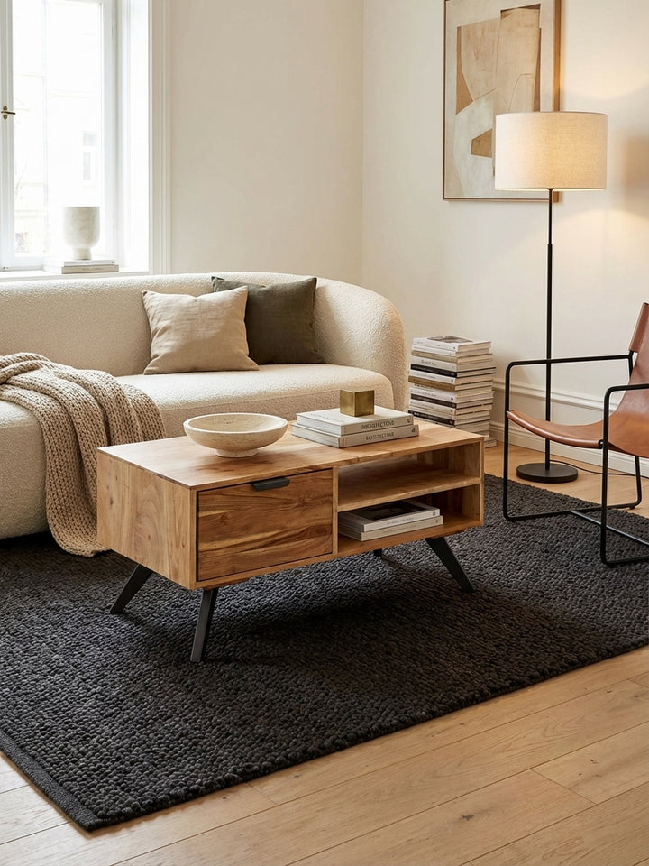 Der Couchtisch aus massivem Akazienholz steht in einem hellen Wohnzimmer vor einem Sofa und bringt mit seiner Maserung und den Metallbeinen eine organisch-moderne Wärme._