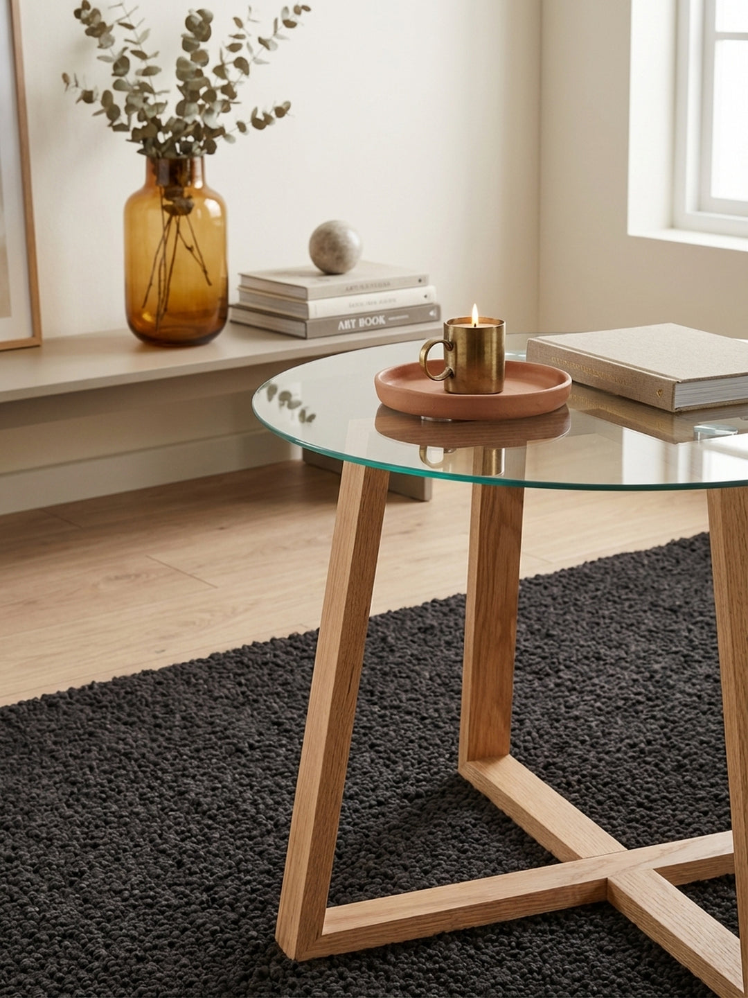 Detailaufnahme der Massivholzstruktur des Eiche-Gestells. Die feine Maserung des Holzes unter der runden Glasplatte des Design-Wohnzimmertisches wird sichtbar._