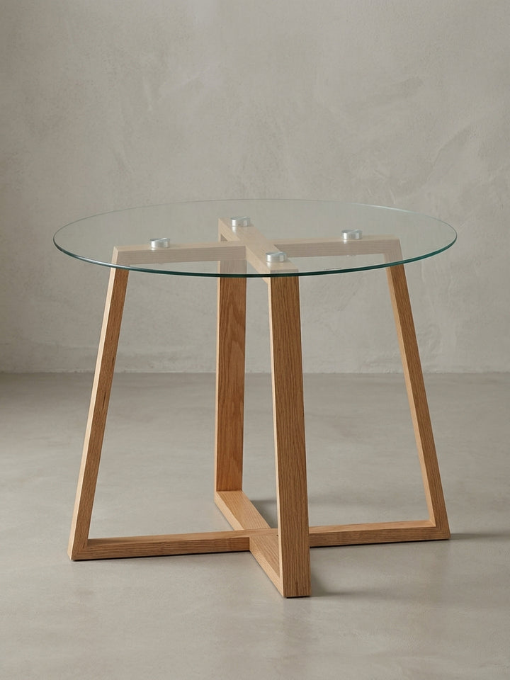 Moderner runder Couchtisch (58 cm) mit Glasplatte und massivem Eichenholzgestell freigestellt vor weißem Hintergrund. Frontansicht des eleganten Designs für das Wohnzimmer._
