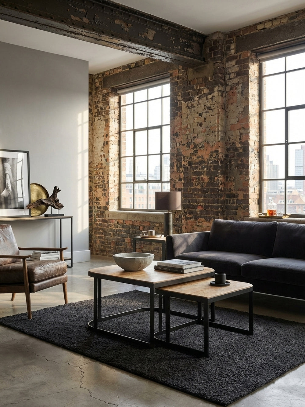Elegantes Couchtisch Set aus Mango Massivholz im Industrie-Stil, stilvoll arrangiert auf einem dunklen Teppich vor einem grauen Sofa in einem hellen Wohnzimmer._