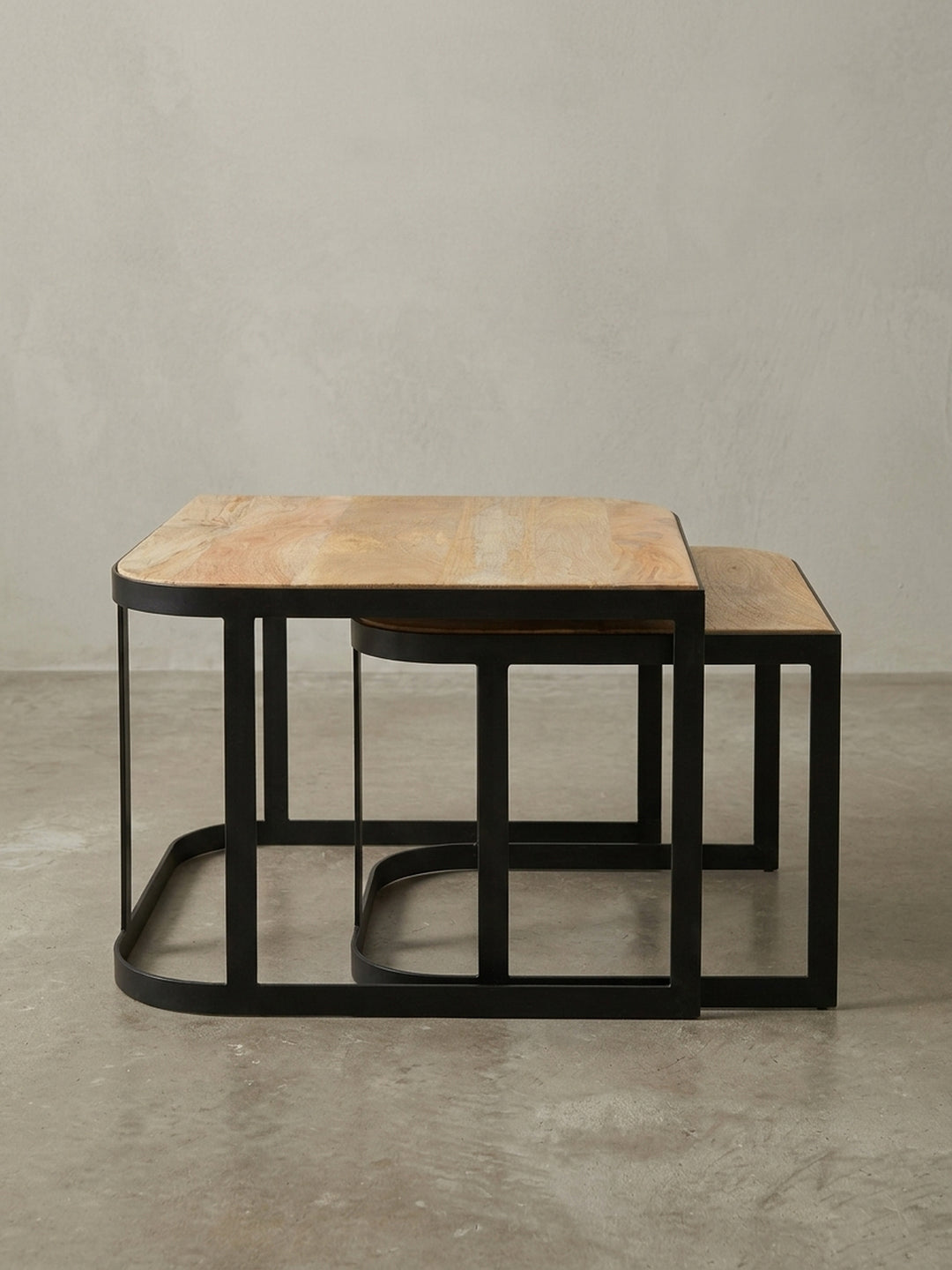 Couchtisch Set aus Mango Massivholz in einer 3/4-Ansicht, die die ineinander geschobene Konstruktion und das minimalistische Design der Metallbeine zeigt._