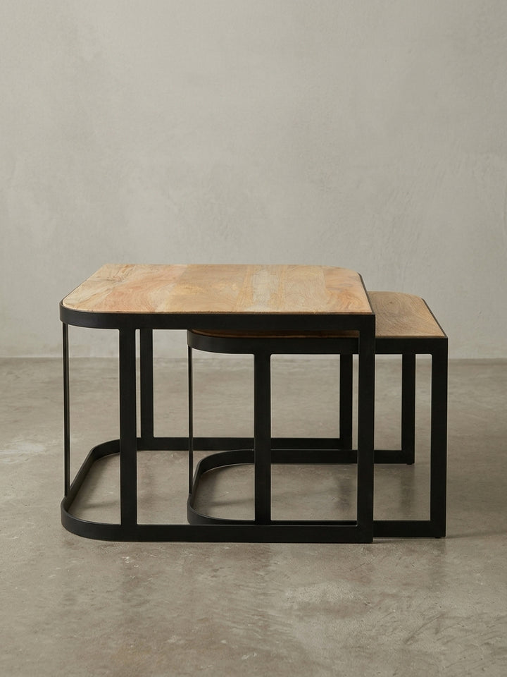 Couchtisch Set aus Mango Massivholz in einer 3/4-Ansicht, die die ineinander geschobene Konstruktion und das minimalistische Design der Metallbeine zeigt._
