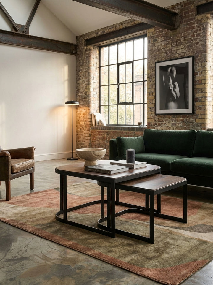 Ein industrieller Satztisch aus Mango Massivholz und schwarzem Metall, stilvoll im Zentrum eines modernen Wohnzimmers mit Sofa und Teppich._