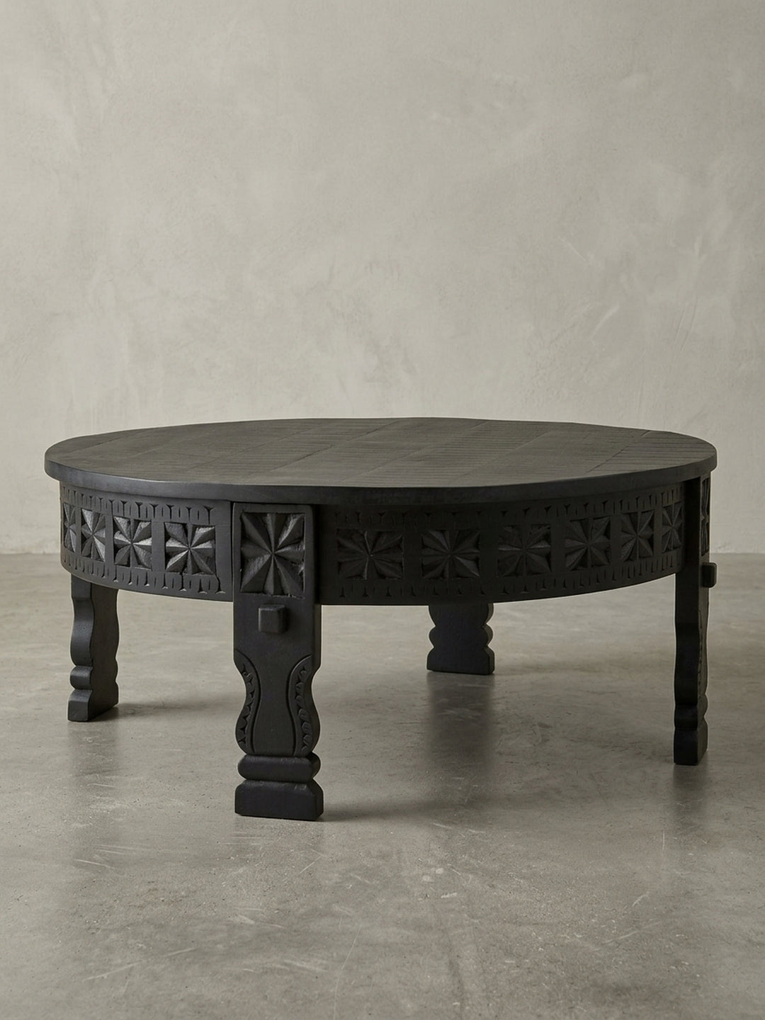 Studioaufnahme des runden Design Couchtischs in Schwarz, 80cm Durchmesser, aus massivem Mangoholz gefertigt, präsentiert auf weißem Hintergrund zur Darstellung der klaren Form._