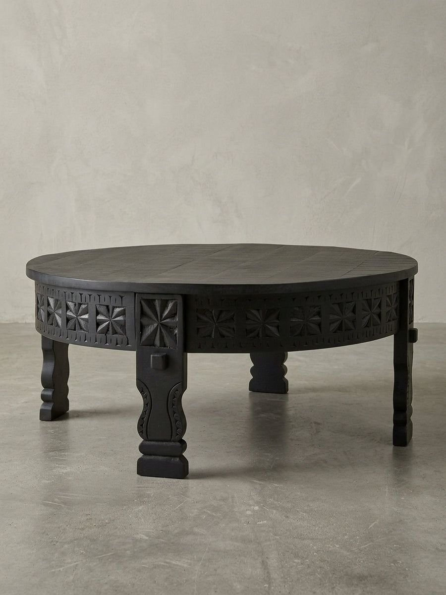 Studioaufnahme des runden Design Couchtischs in Schwarz, 80cm Durchmesser, aus massivem Mangoholz gefertigt, präsentiert auf weißem Hintergrund zur Darstellung der klaren Form._