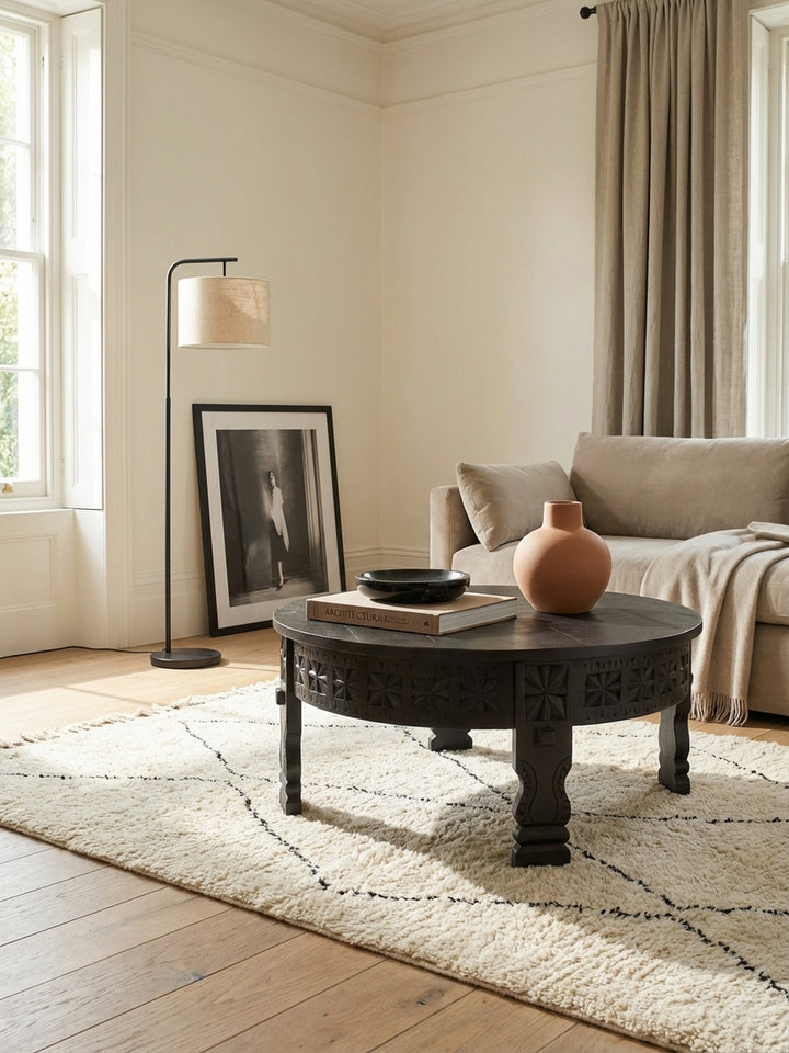 Draufsicht auf den schwarzen 80cm Salontisch aus Mangoholz, der als zentrales Element auf einem texturierten Teppich im Wohnzimmer dient und die aufwendigen Schnitzereien zeigt._