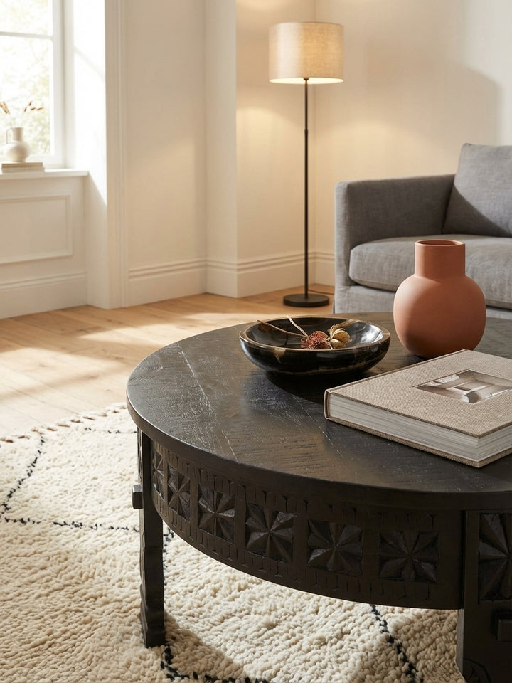 Makroaufnahme der handgeschnitzten Oberflächenstruktur des schwarzen Mango-Massivholz-Couchtischs, die die feine Handwerkskunst und die matte Lackierung des Holzes hervorhebt._