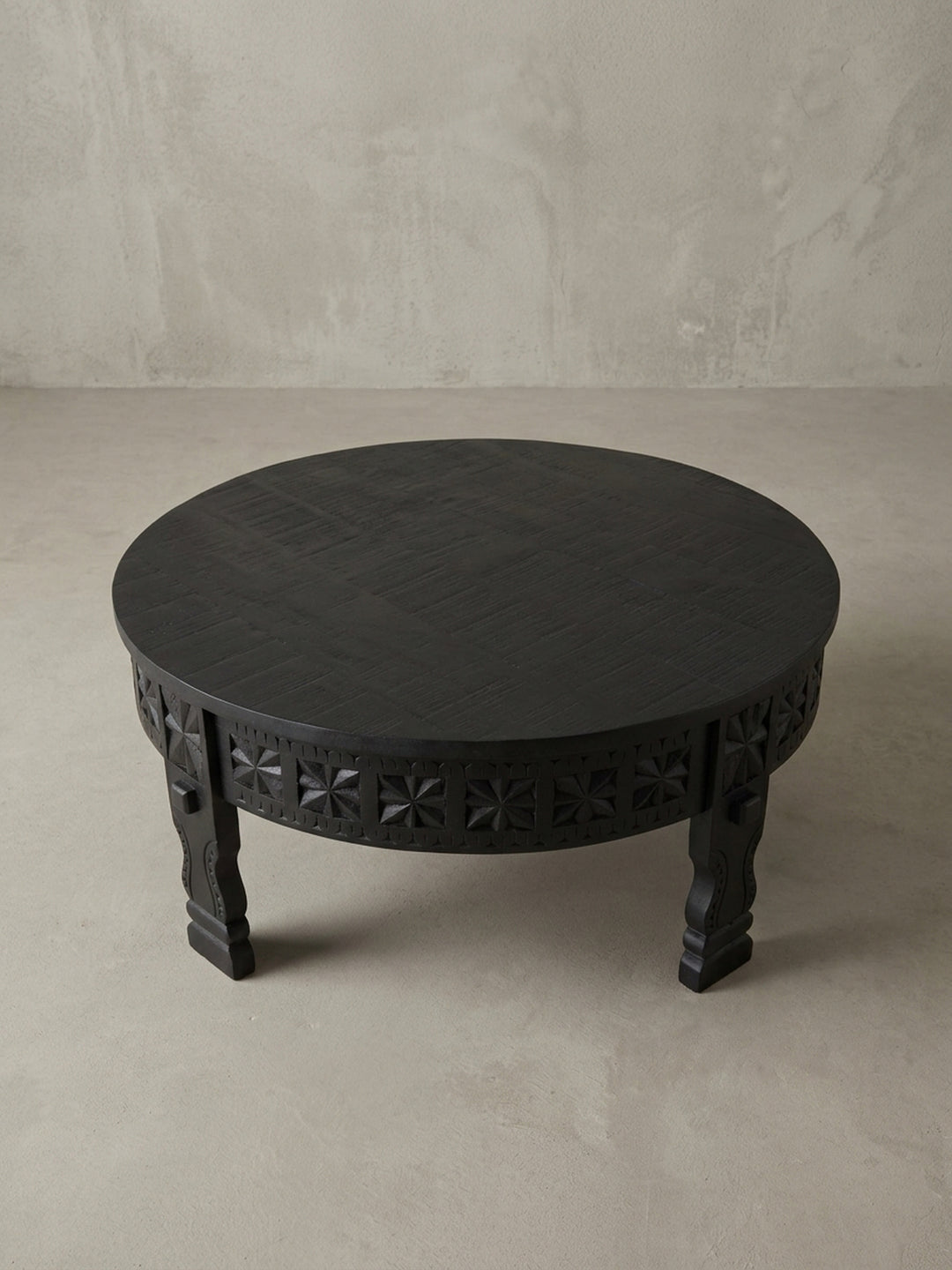 Detailansicht eines der geschnitzten Beine des orientalischen Couchtischs, die die traditionelle Handwerkskunst und die massive Qualität des schwarzen Mangoholzes unterstreicht._