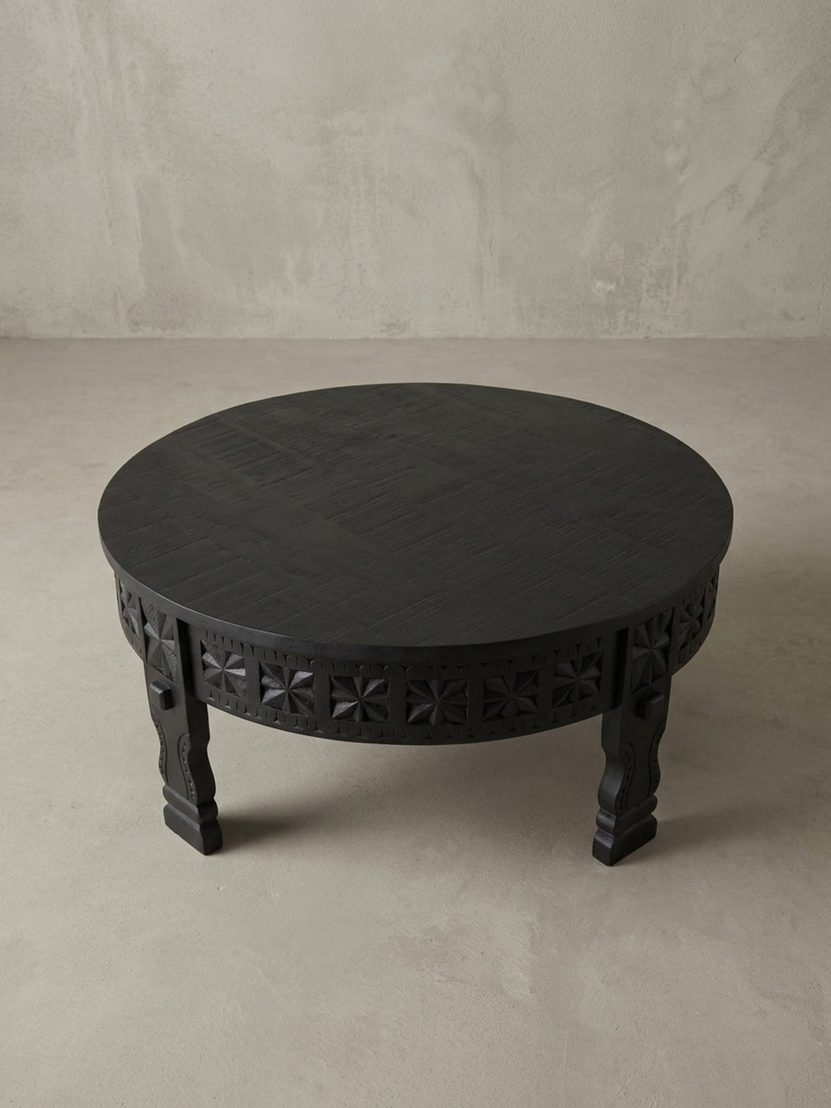 Detailansicht eines der geschnitzten Beine des orientalischen Couchtischs, die die traditionelle Handwerkskunst und die massive Qualität des schwarzen Mangoholzes unterstreicht.