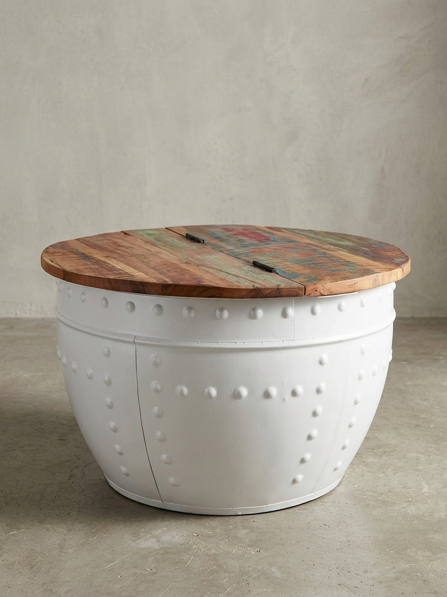 Design Wohnzimmertisch in 3/4-Ansicht, der den genieteten weißen Metallkorpus und die mehrfarbige Massivholzplatte aus Mango hervorhebt._