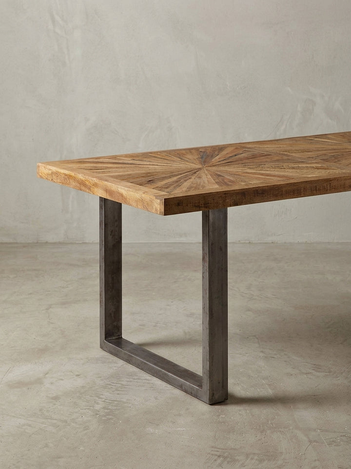 Alternative Perspektive des Esstisches, die das spannende Farbspiel des natürlichen Mangoholzes und die industrielle Textur der rustikalen Edelstahl-Beine perfekt einfängt._