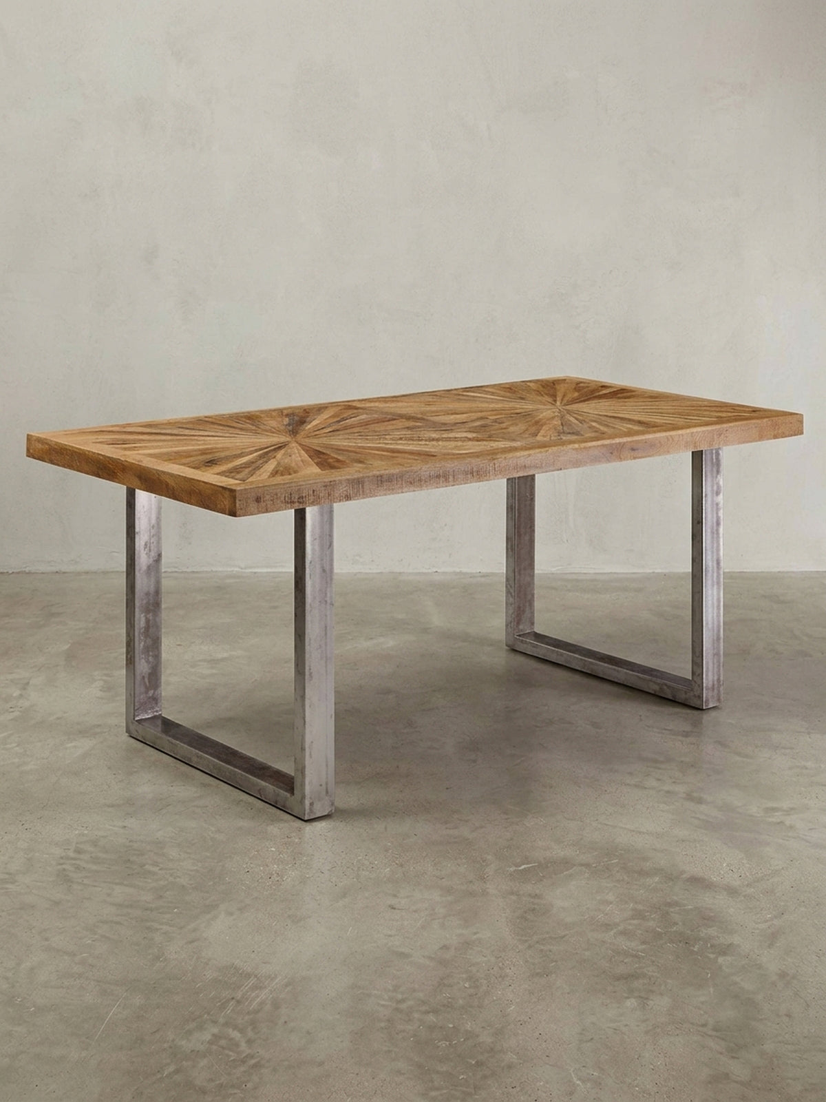 Rechteckiger Esstisch im Industrial Design auf weißem Hintergrund. Die Kombination aus massiver Mangoholz-Platte und U-förmigem Edelstahl-Gestell im Used-Look wirkt sehr markant._