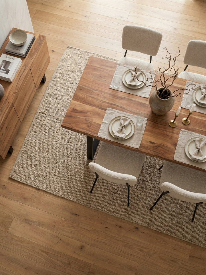 Essgruppe von oben mit 140x80 cm Holztisch aus Akazie, passender Bank und hellen Stühlen auf einem beigefarbenen Teppich arrangiert._