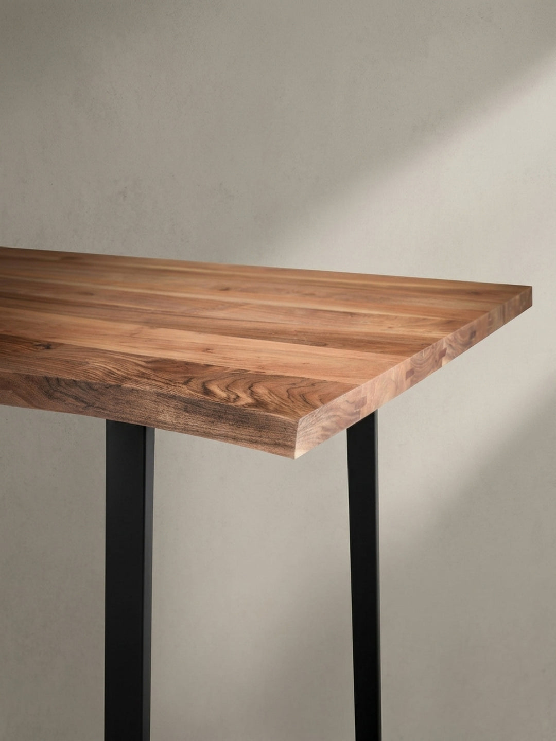 Industrieller Esstisch aus Akazie und Metall aus einer anderen Perspektive, die das Zusammenspiel von natürlichem Holz und schwarzem Gestell betont._