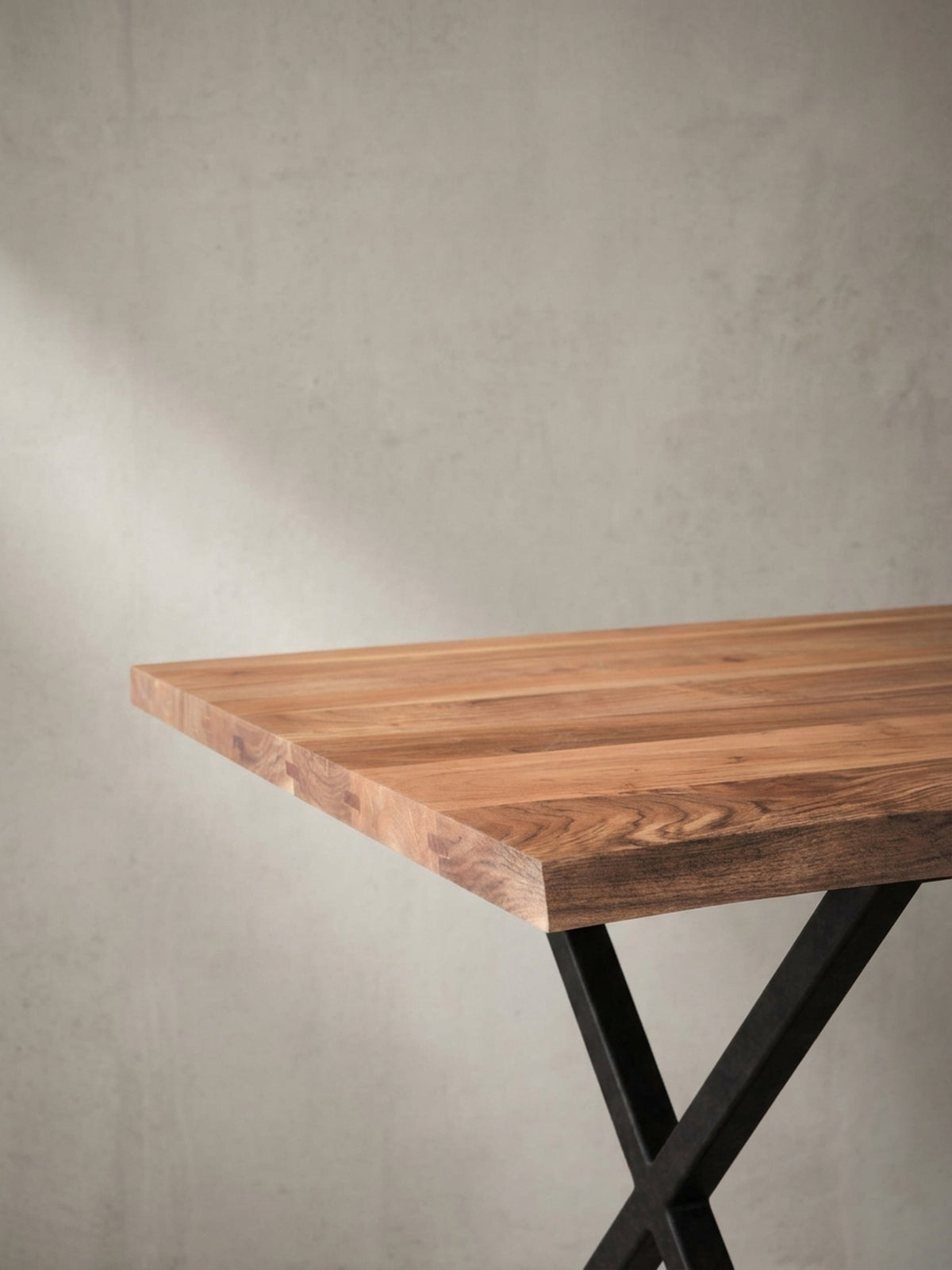 Alternative Perspektive auf den Holztisch mit Baumkante, die den Kontrast zwischen dem warmen Akazienholz und dem kühlen, schwarzen Metall betont.