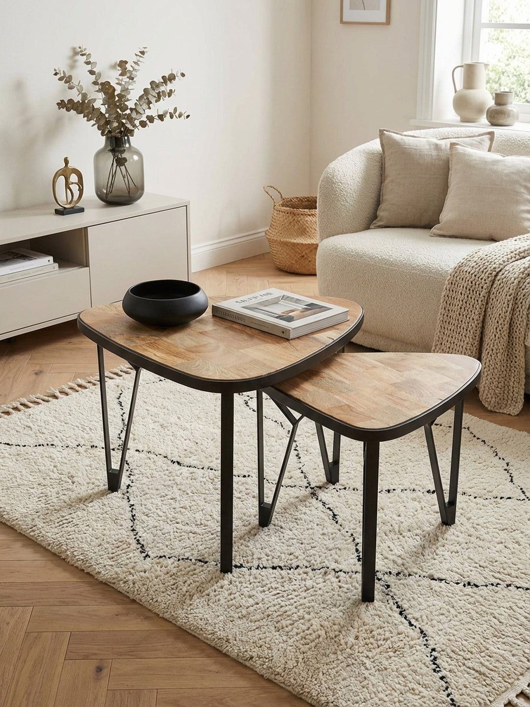 Die Anordnung der dreieckigen Satztische aus Holz und Metall von oben betrachtet, zeigt die platzsparende Nistfunktion im modernen Wohnbereich vor einem Sofa._