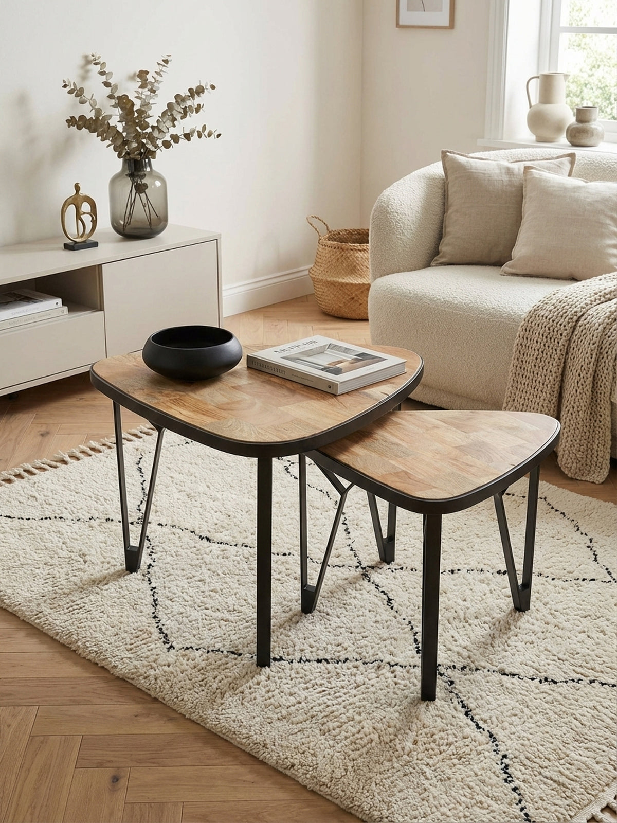 Die Anordnung der dreieckigen Satztische aus Holz und Metall von oben betrachtet, zeigt die platzsparende Nistfunktion im modernen Wohnbereich vor einem Sofa.