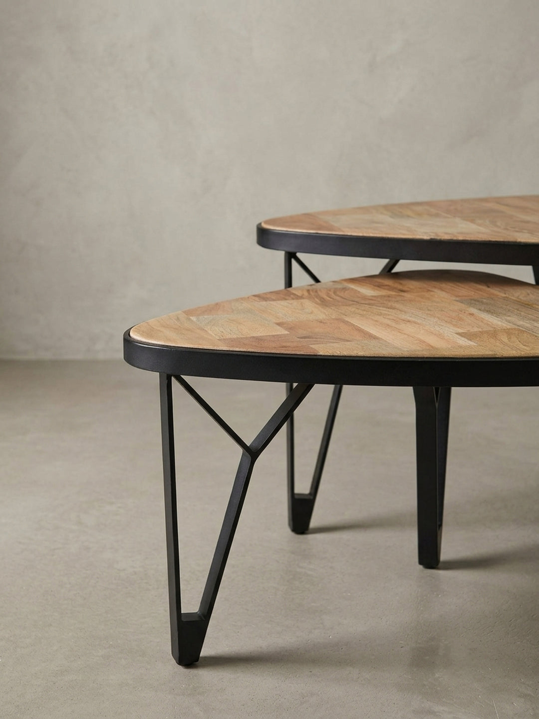 Nahaufnahme der abgerundeten Ecke und des schwarzen Metallrahmens, der die Tischplatte aus massivem Akazien- und Mangoholz elegant einfasst._