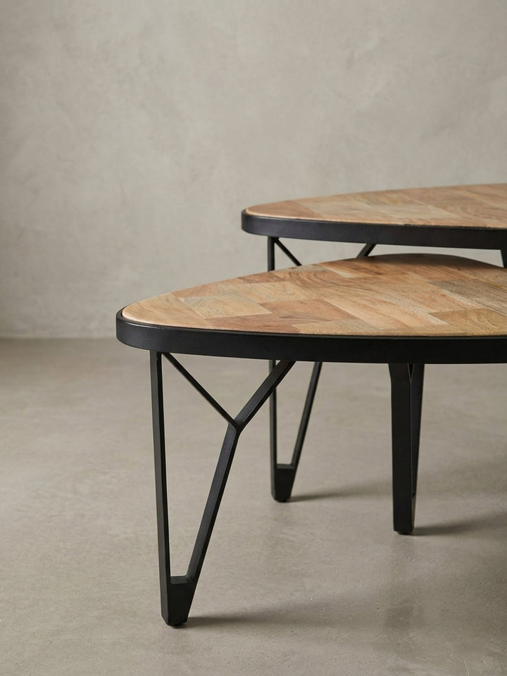 Nahaufnahme der abgerundeten Ecke und des schwarzen Metallrahmens, der die Tischplatte aus massivem Akazien- und Mangoholz elegant einfasst._
