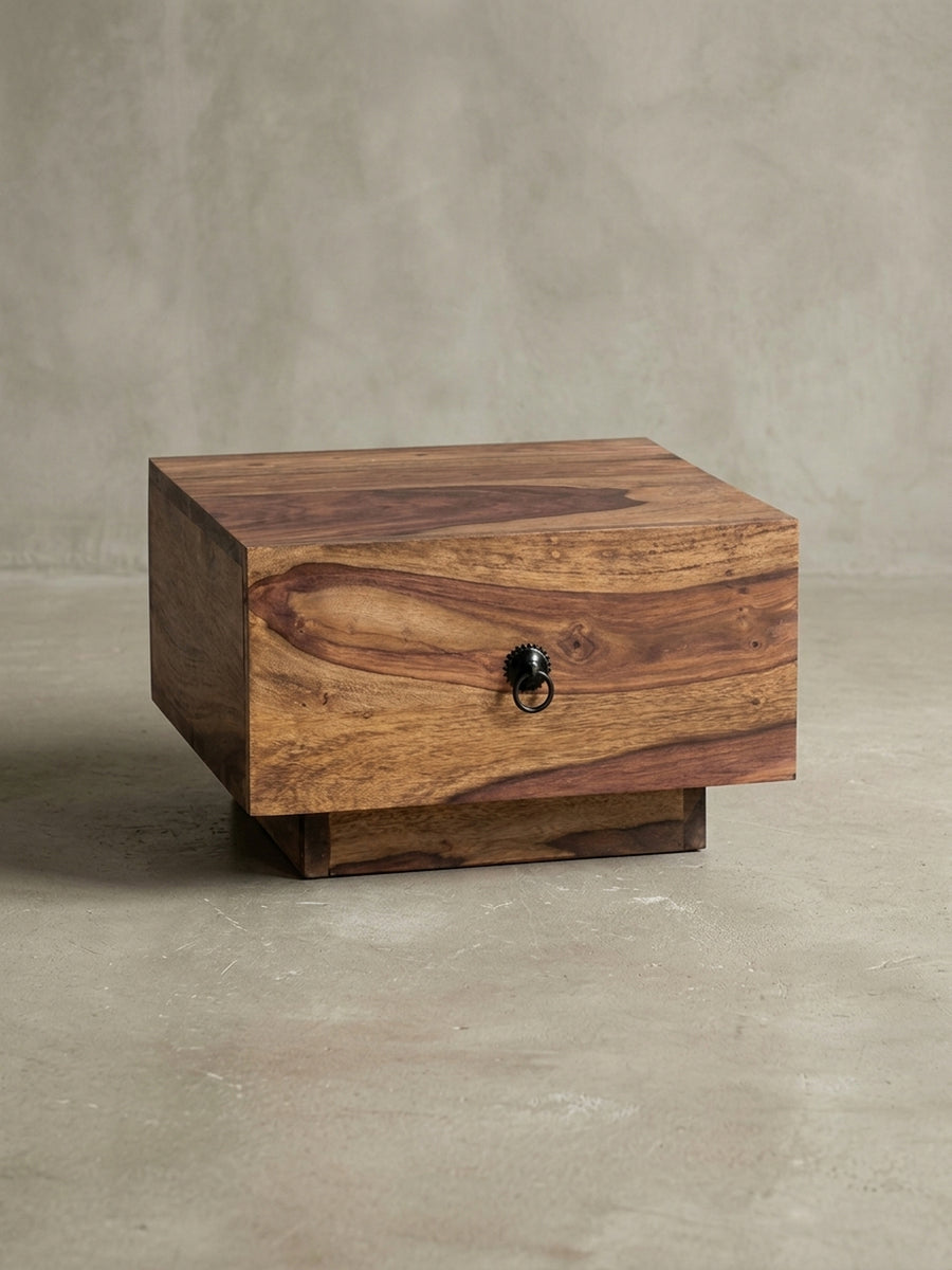 Nachttisch aus warmem Sheesham-Massivholz mit markanter Maserung mit Schublade und Ablagefach auf neutralem Betonhintergrund Frontalansicht 40x40x25 cm_