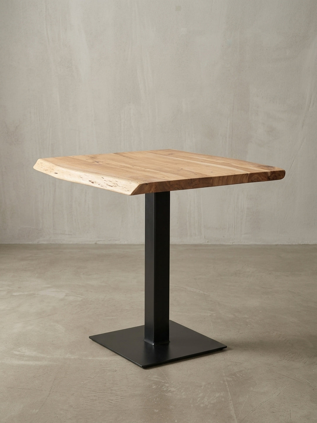 Design-Küchentisch aus Akazie in einer 3/4-Ansicht, die die einzigartige Baumkante und den Kontrast zwischen der Holzplatte und dem mattschwarzen Edelstahlgestell zeigt._
