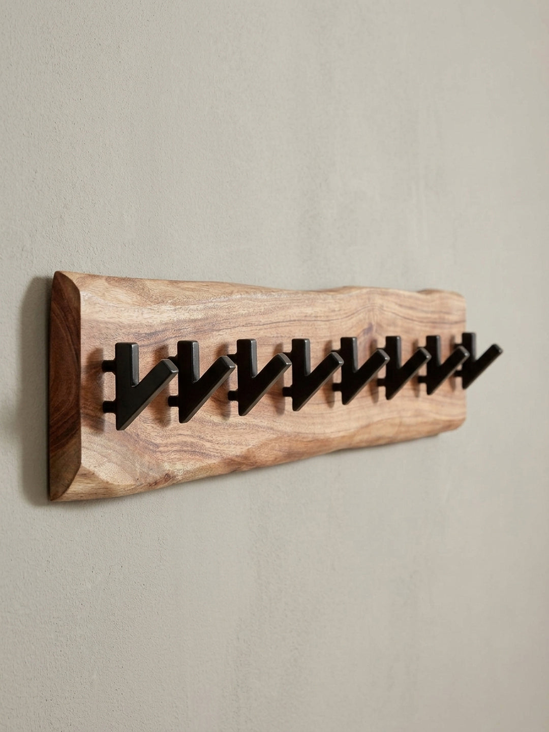 Dynamische Ansicht der Flurgarderobe, die das Zusammenspiel von warmem Akazienholz und den geometrischen, mattschwarzen Haken betont._