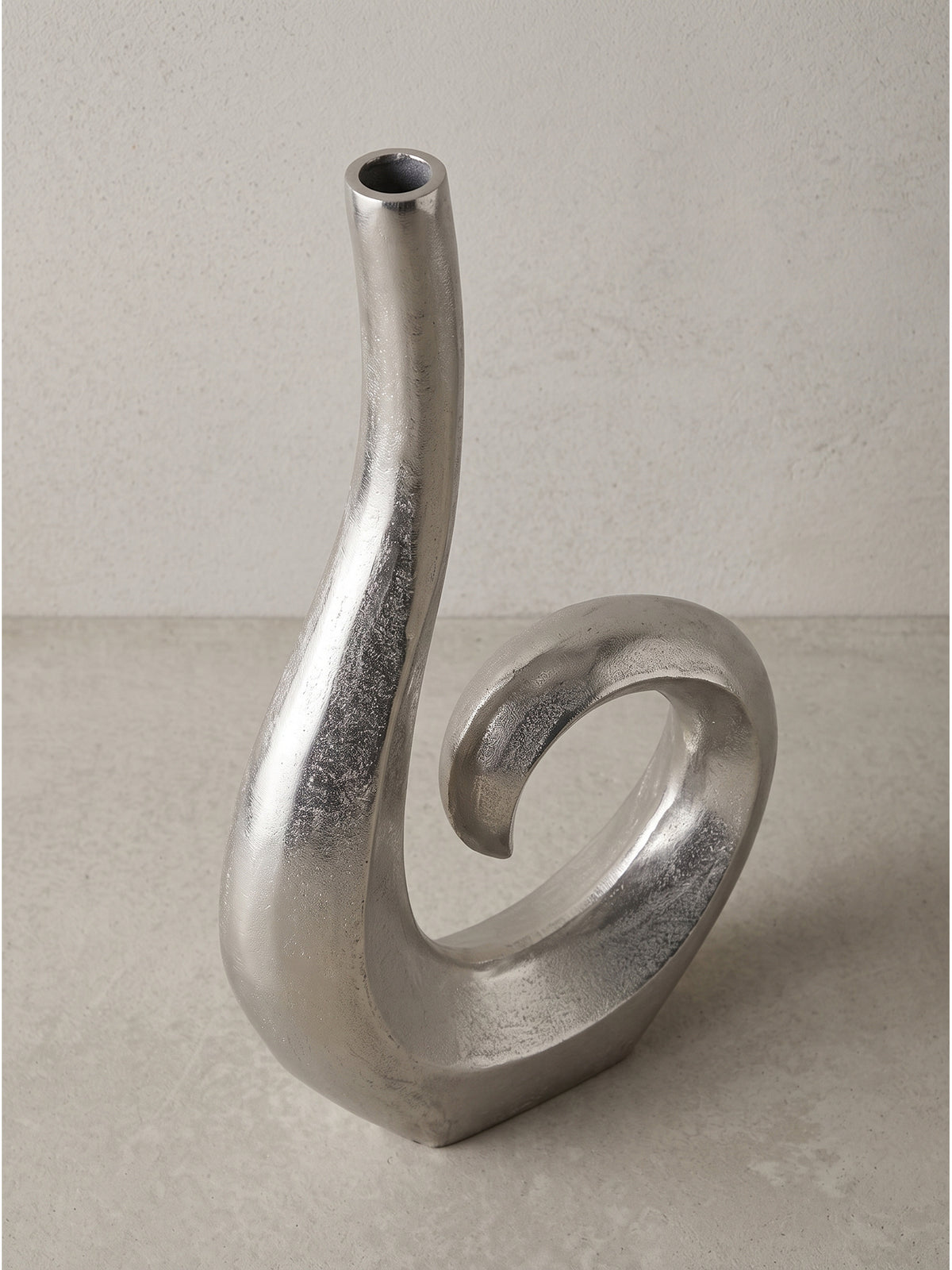 Skulpturale Blumenvase aus Alu in Silber im Halbprofil zeigt das markante Design vor neutralem Hintergrund._