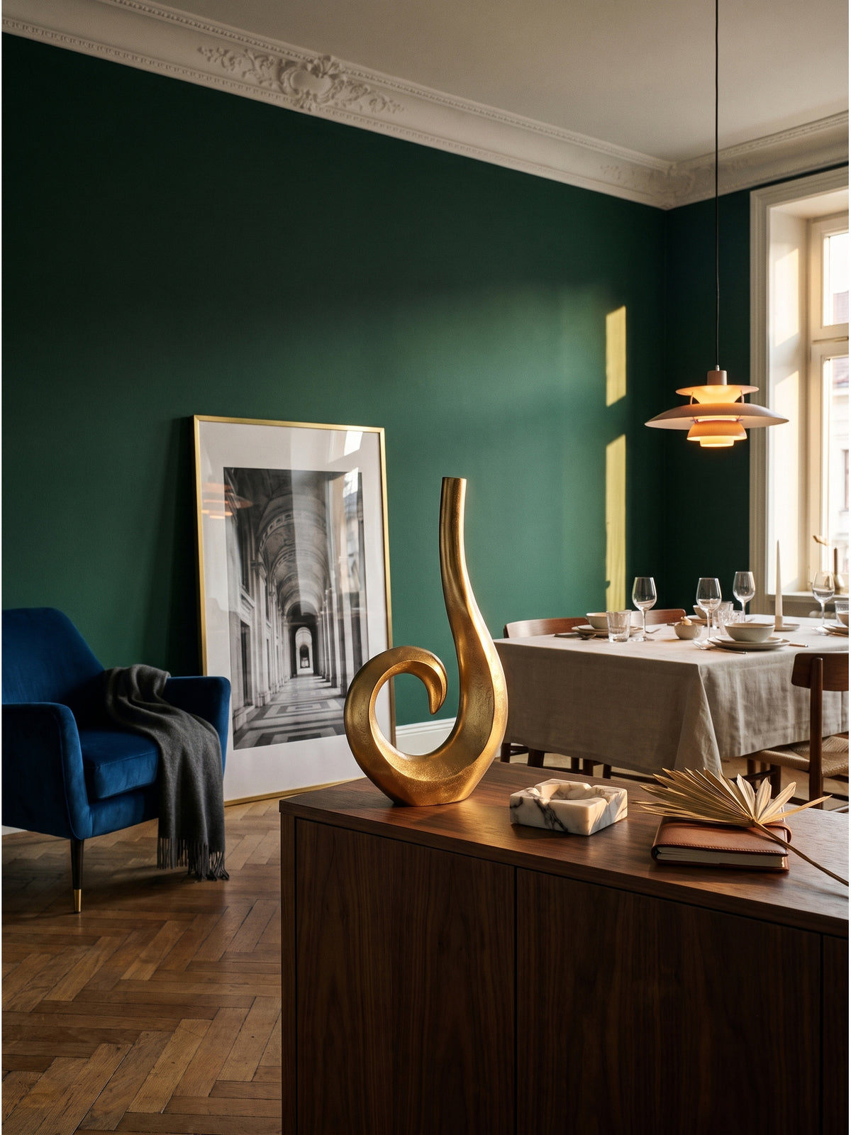 Große Deko Vase 47 cm in Gold Spirale auf einem dunklen Nussbaum-Sideboard vor smaragdgrüner Wand im eleganten Wohnzimmer._