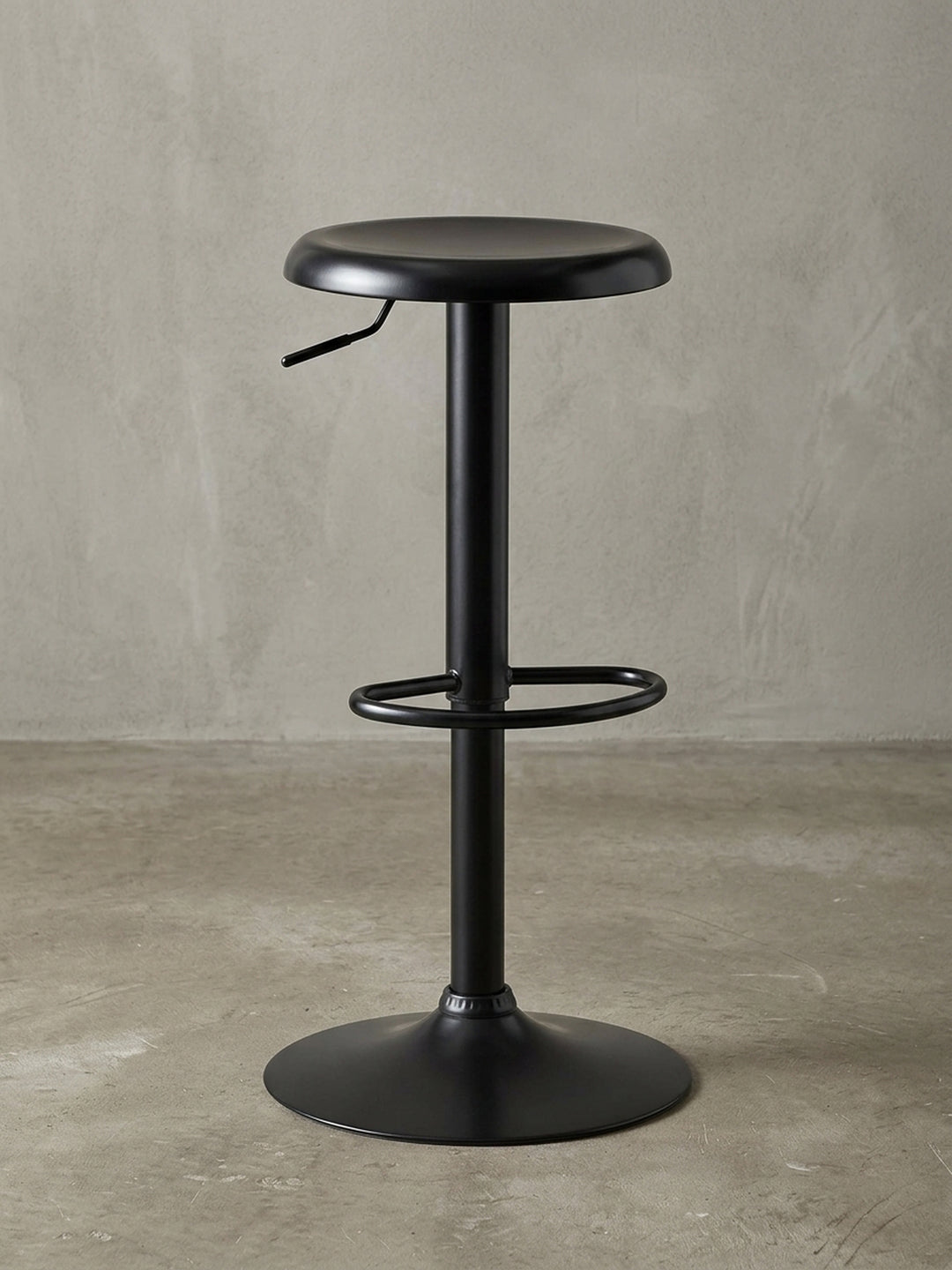 3/4-Ansicht des schwarzen Metall-Barhockers, der die runde Sitzfläche, den praktischen Verstellhebel und die elegante Verbindung zur Mittelsäule detailliert darstellt._