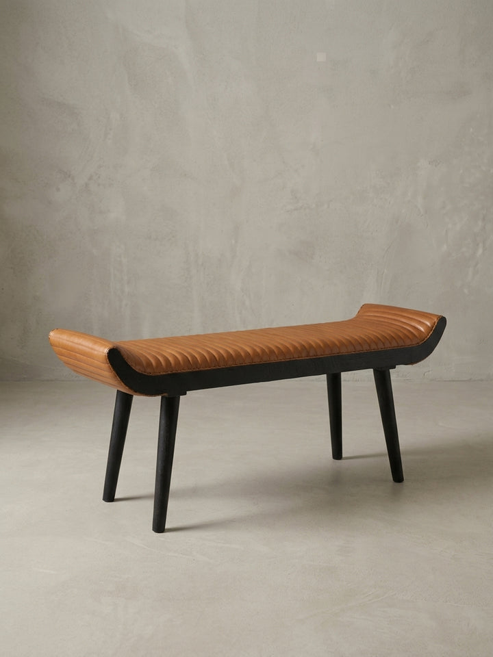 Seitenansicht der Polsterbank, die das schlanke Profil und die Höhe von 51 cm zeigt. Die konisch zulaufenden Beine aus Mangoholz unterstreichen das Design._