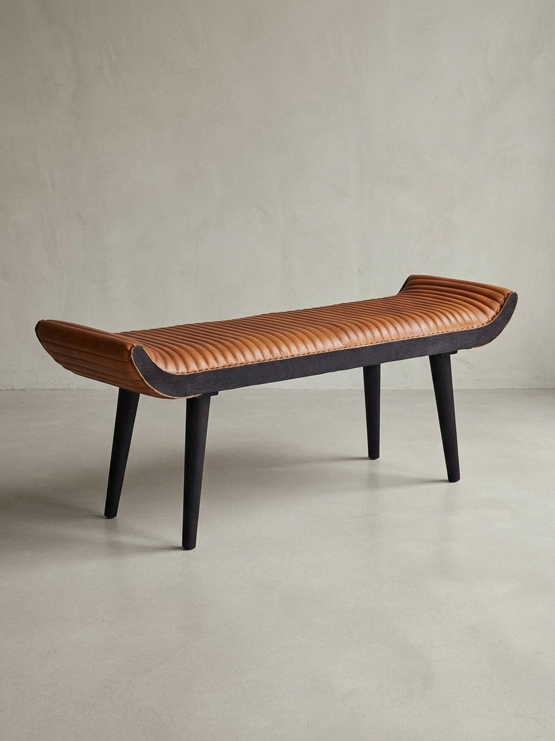 Freigestellte Frontansicht der modernen Sitzbank 125x51x38 cm. Das cognacfarbene Echtleder und die dunklen Massivholz-Beine bilden einen eleganten Kontrast._