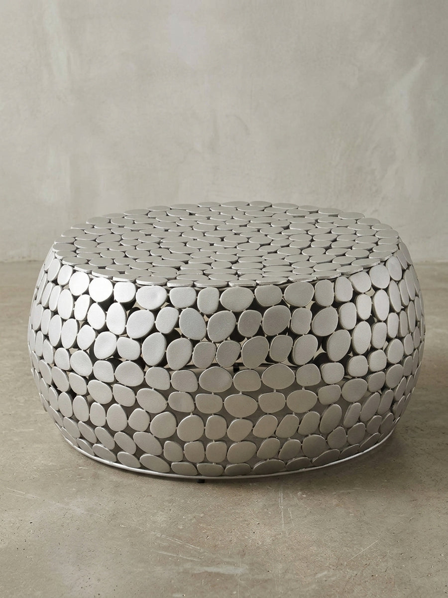 Design Wohnzimmertisch aus Aluminium in 3/4-Ansicht, die die plastische Oberflächenstruktur und die niedrige Bauhöhe von 32 cm hervorhebt._