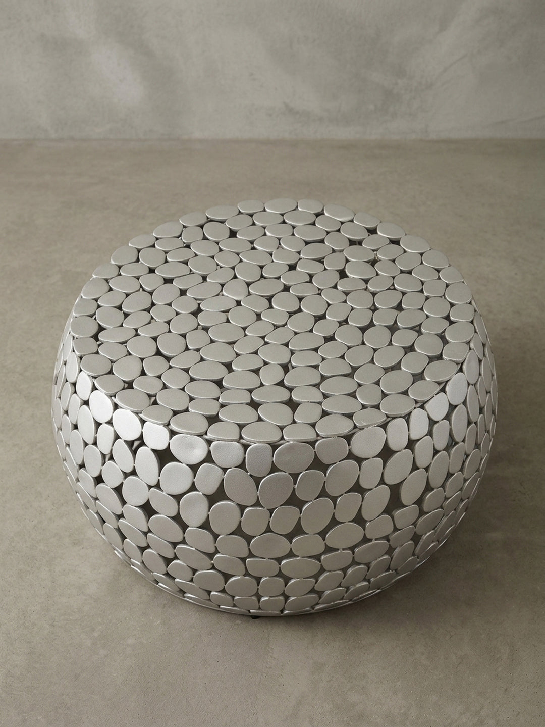 Detailaufnahme der Tischplatte des Couchtisches, die die flachen, aneinander gefügten Aluminium-Elemente im Kiesel-Design zeigt._