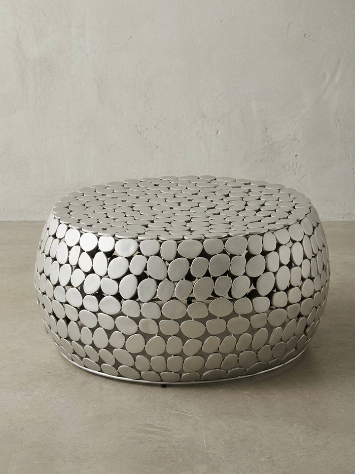 Freigestellter Couchtisch Metall Silber rund, zeigt die organische Kieselstein-Optik und die moderne Trommelform vor weißem Hintergrund._