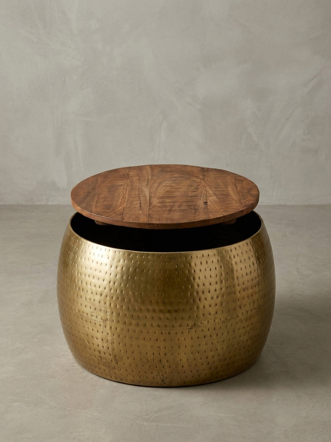 Nahaufnahme des goldenen Couchtisches, die das einzigartige gehämmerte Finish des Metallkorpus und den warmen Kontrast zum dunklen Mangoholz hervorhebt._