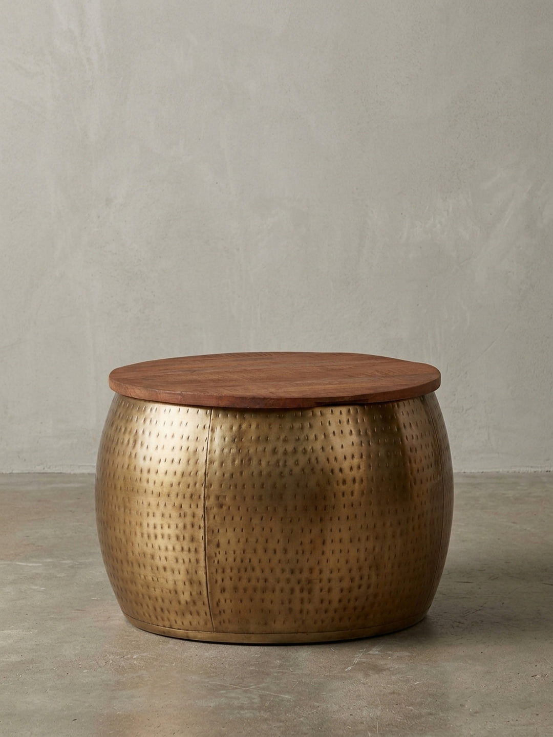 Freigestellter runder Couchtisch mit goldenem, gehämmertem Metallkorpus und einer Tischplatte aus massivem Mangoholz, Frontansicht auf weißem Hintergrund._