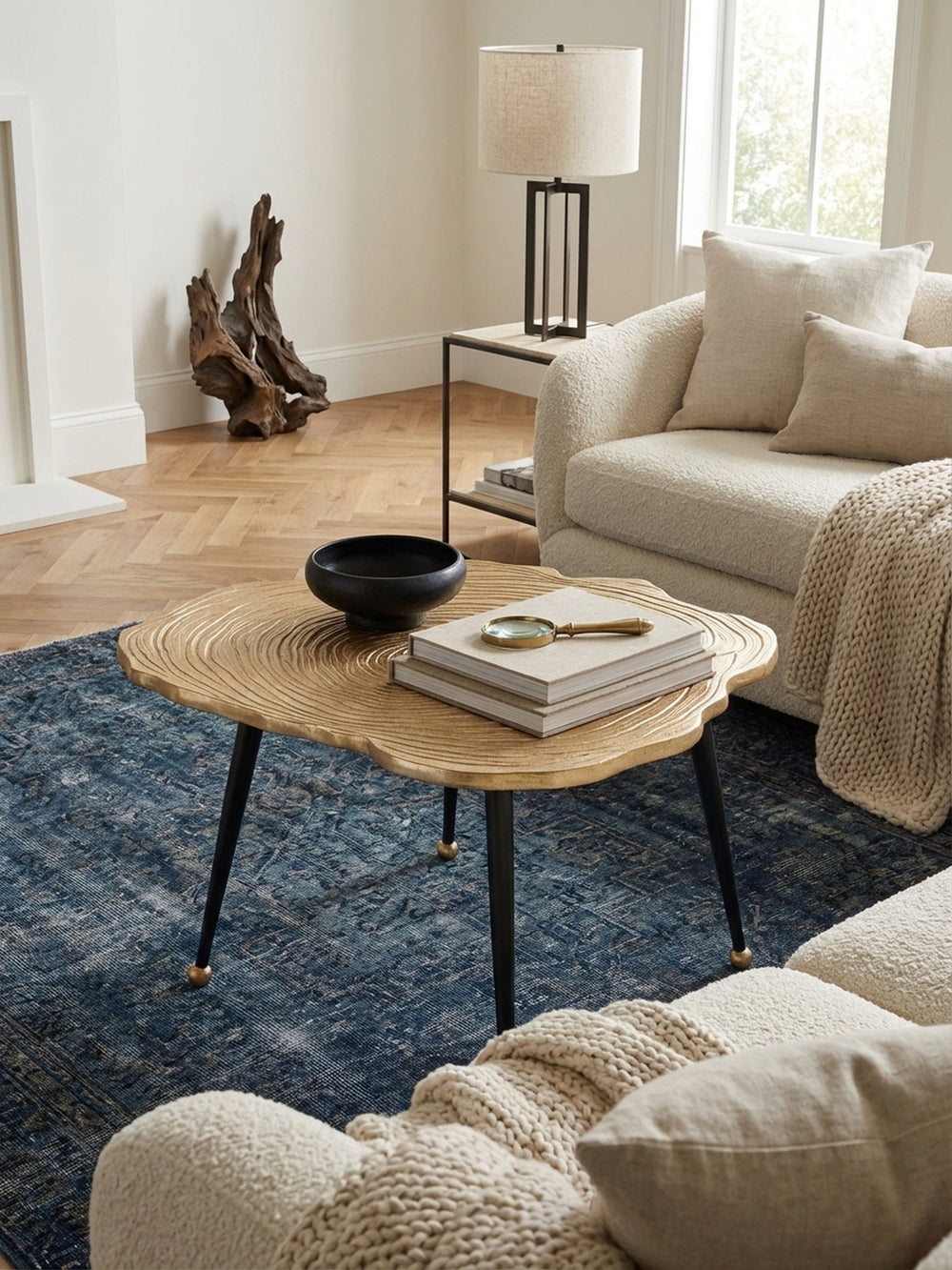 Draufsicht auf den runden Design-Couchtisch aus goldenem Aluminium, der mit Teekanne und Vase dekoriert ist und die organische Form der Tischplatte zeigt._