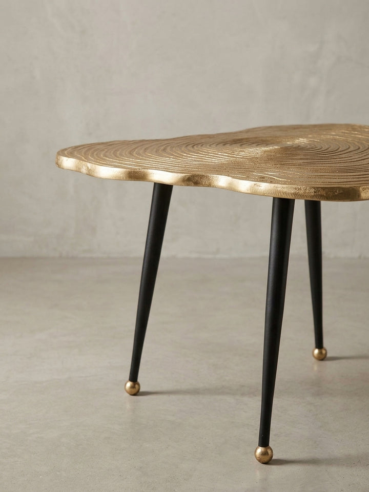 Nahaufnahme eines der schlanken, schwarzen Tischbeine mit dem dekorativen, kugelförmigen Fuß in Gold, ein Detail des modernen Kaffeetisch-Designs._