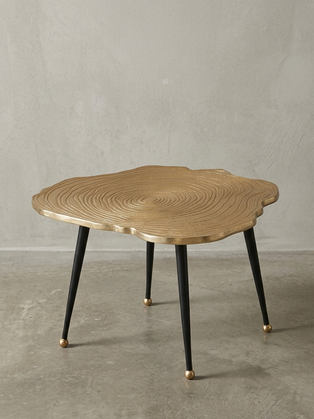 Moderner Couchtisch 64x37 cm aus gold-lackiertem Aluminium mit schwarzen Beinen, organische Baumscheiben-Form, freigestellt auf weißem Hintergrund._