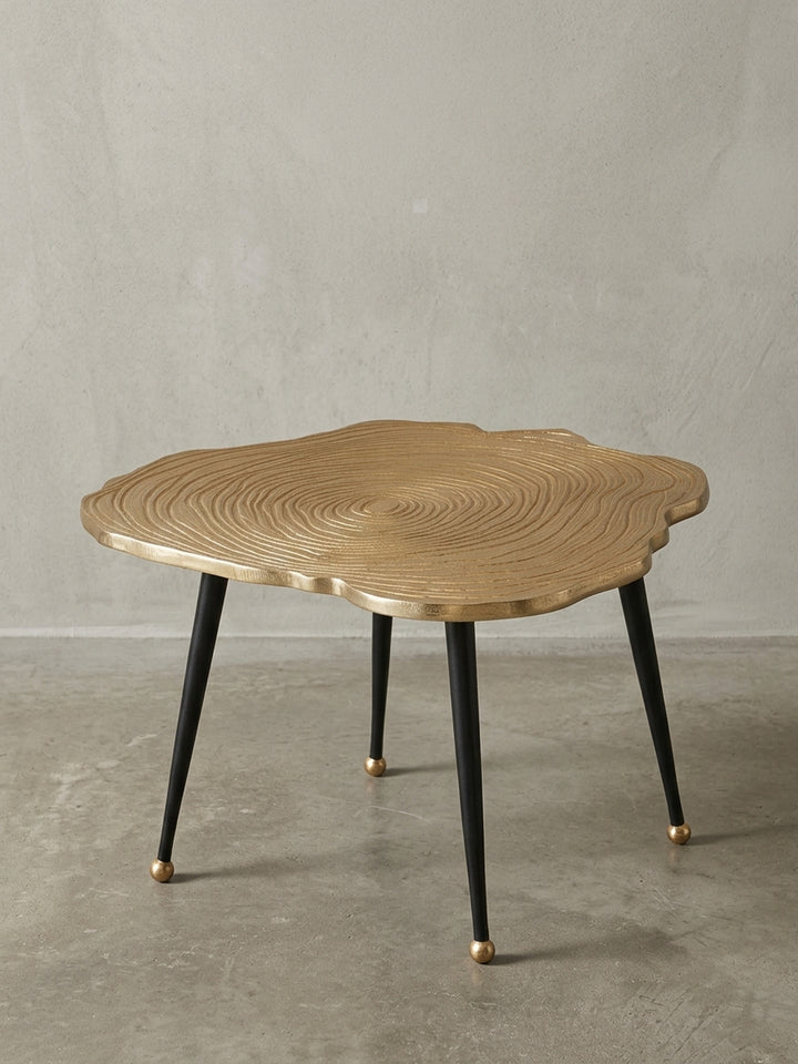 Moderner Couchtisch 64x37 cm aus gold-lackiertem Aluminium mit schwarzen Beinen, organische Baumscheiben-Form, freigestellt auf weißem Hintergrund._