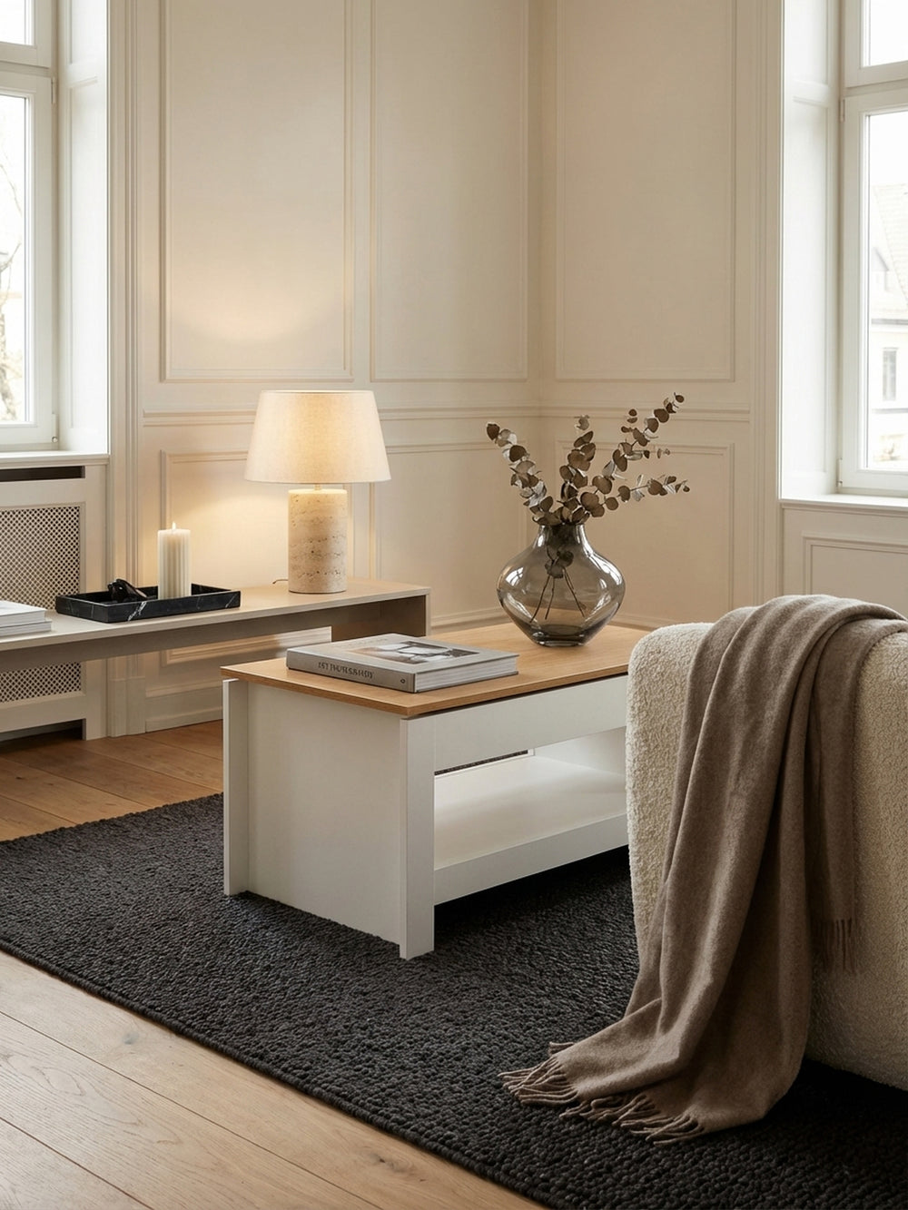 Moderner Couchtisch in Weiß mit Eiche-Tischplatte, elegant in einem hellen Wohnzimmer mit beigem Sofa und dunklem Teppich platziert._