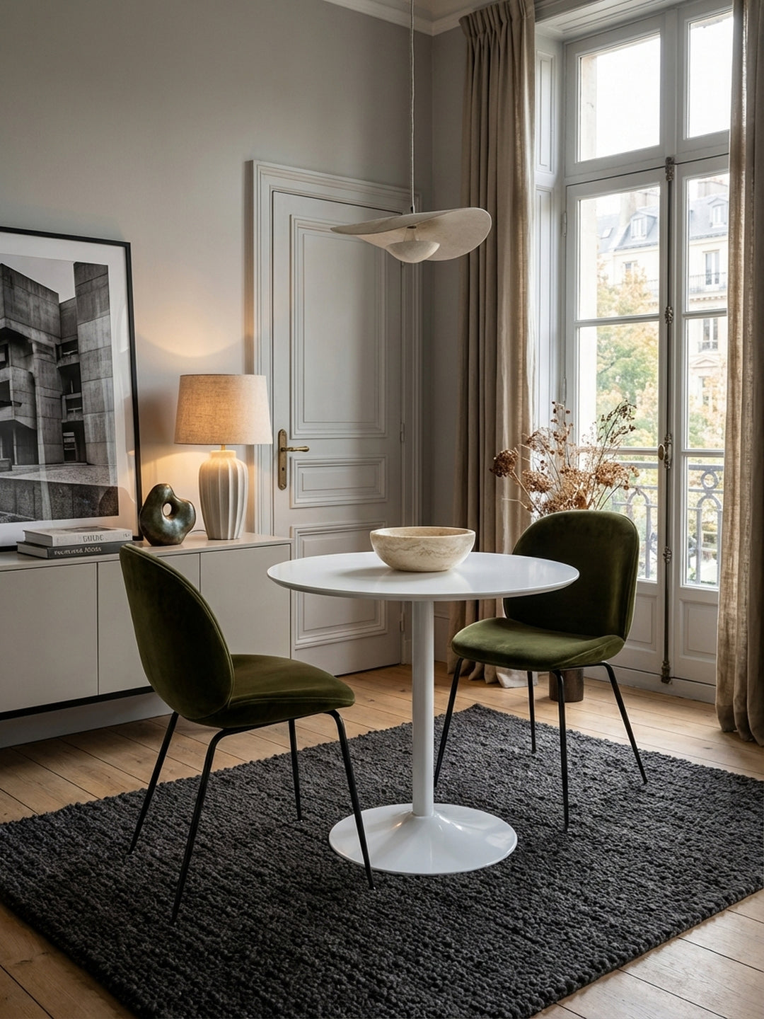 Moderner runder Esstisch in Weiß Hochglanz, elegant in Szene gesetzt in einem minimalistischen Esszimmer mit zwei grauen Samtstühlen und dezenter Dekoration._